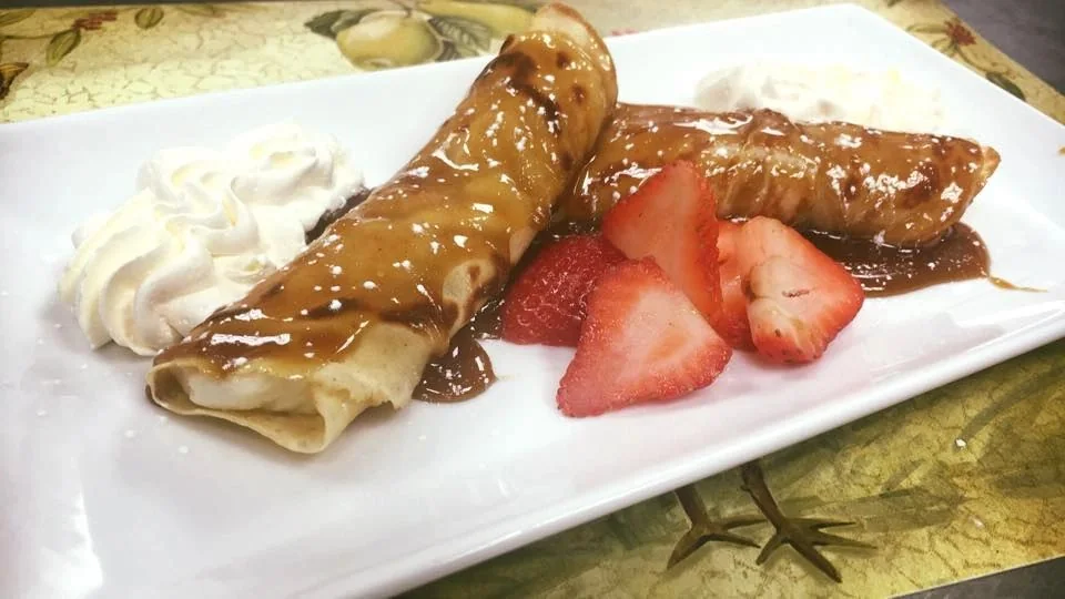 Savoury breakfast crepes finished with caramel sauce, strawberries and cream